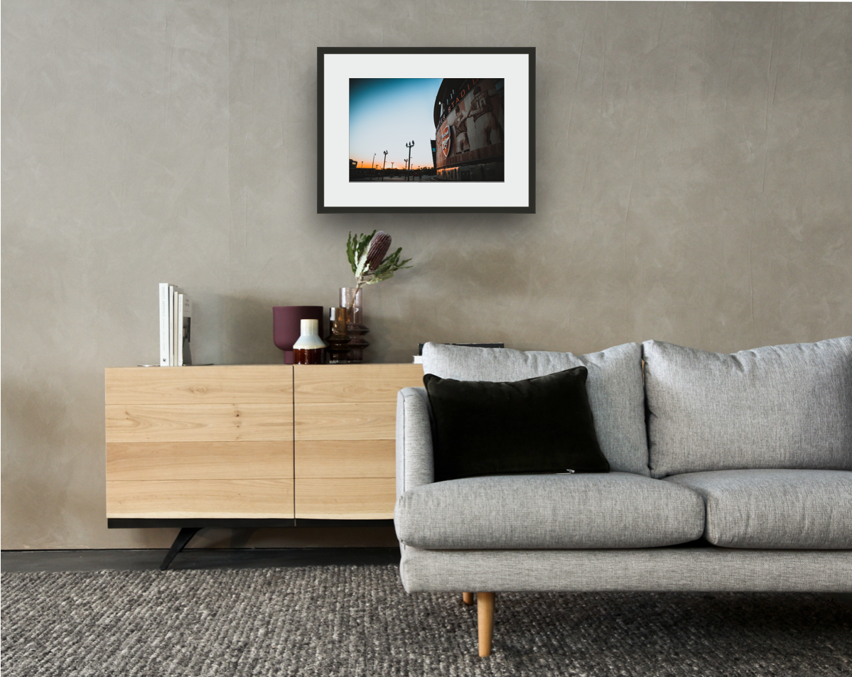 Framed and mounted photograph of Arsenal's Emirates Stadium in North London above a sofa and a cupboard.