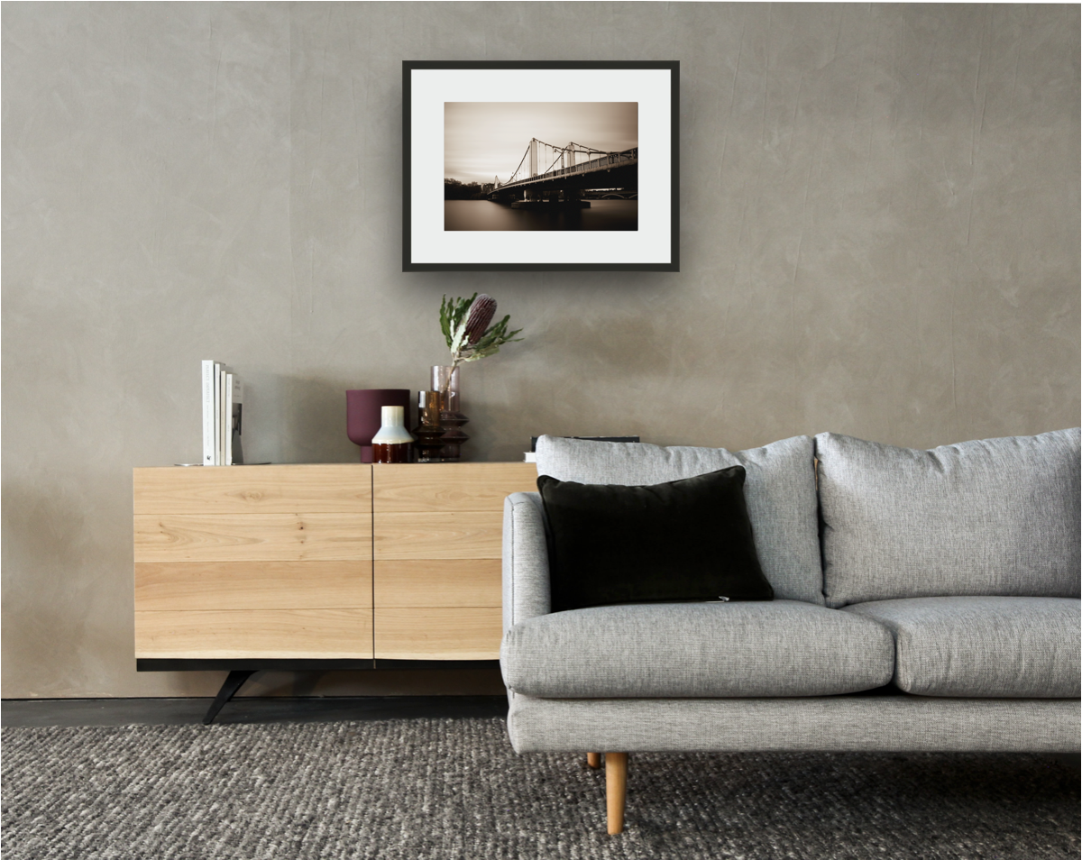 Framed and mounted photograph of Chelsea Bridge on the river Thames in South West London hanging on a wall above a sofa and cupboard