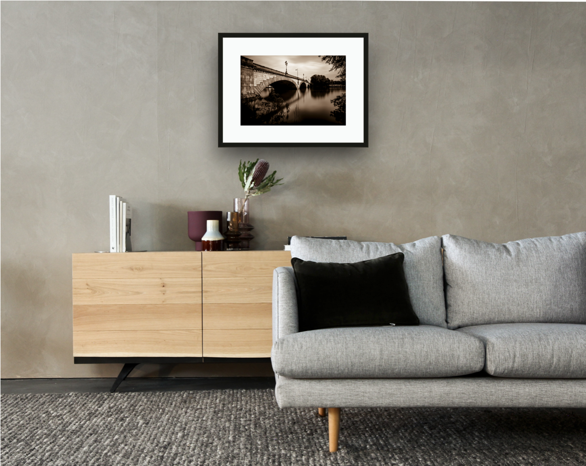 Framed and mounted photograph of kew bridge on the river thames in south west london hanging on a wall above a sofa and cupboard