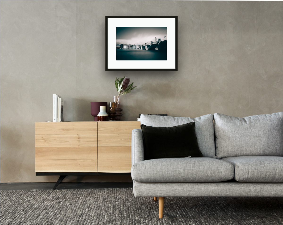 Framed and mounted photograph of Southwark Bridge on the river Thames in London hanging on a wall above a sofa and cupboard