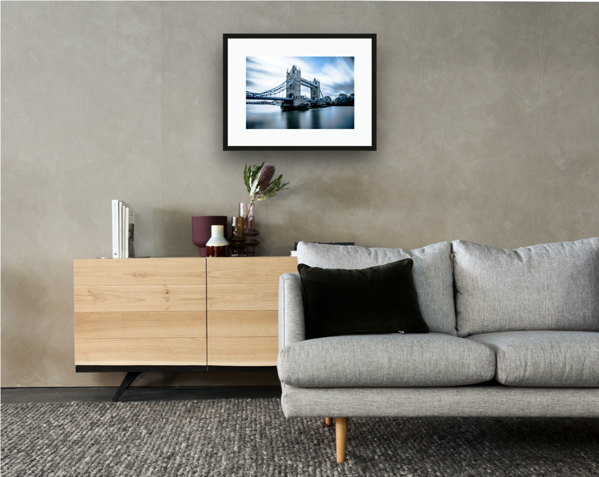 Framed and mounted photograph of Tower Bridge on the river Thames in central London hanging on a wall above a sofa and cupboard